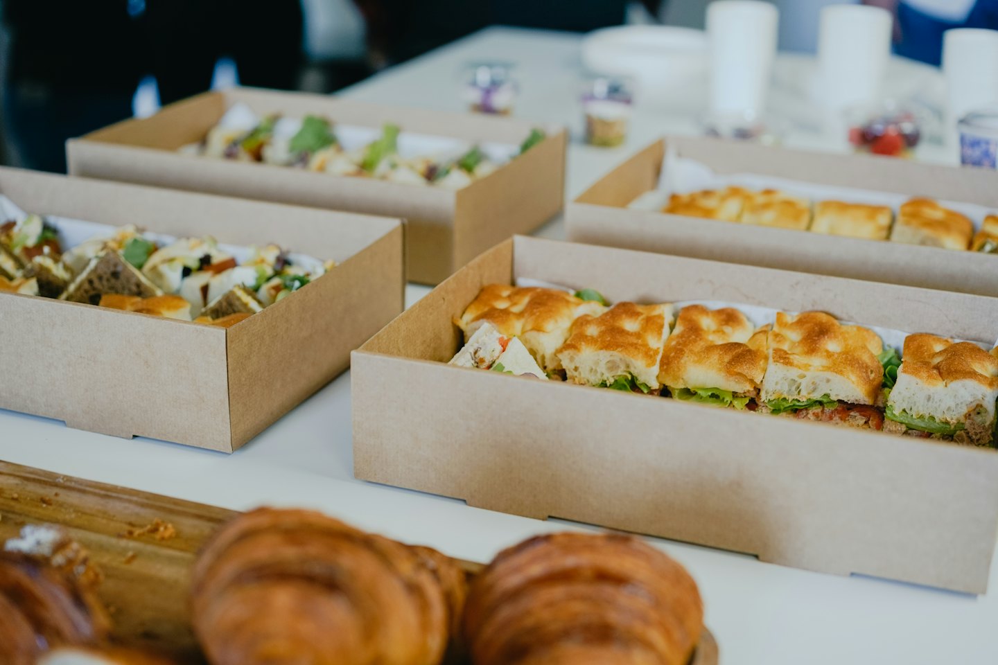 Boîtes à lunch traiteur avec sandwichs et pâtisseries sur une table.