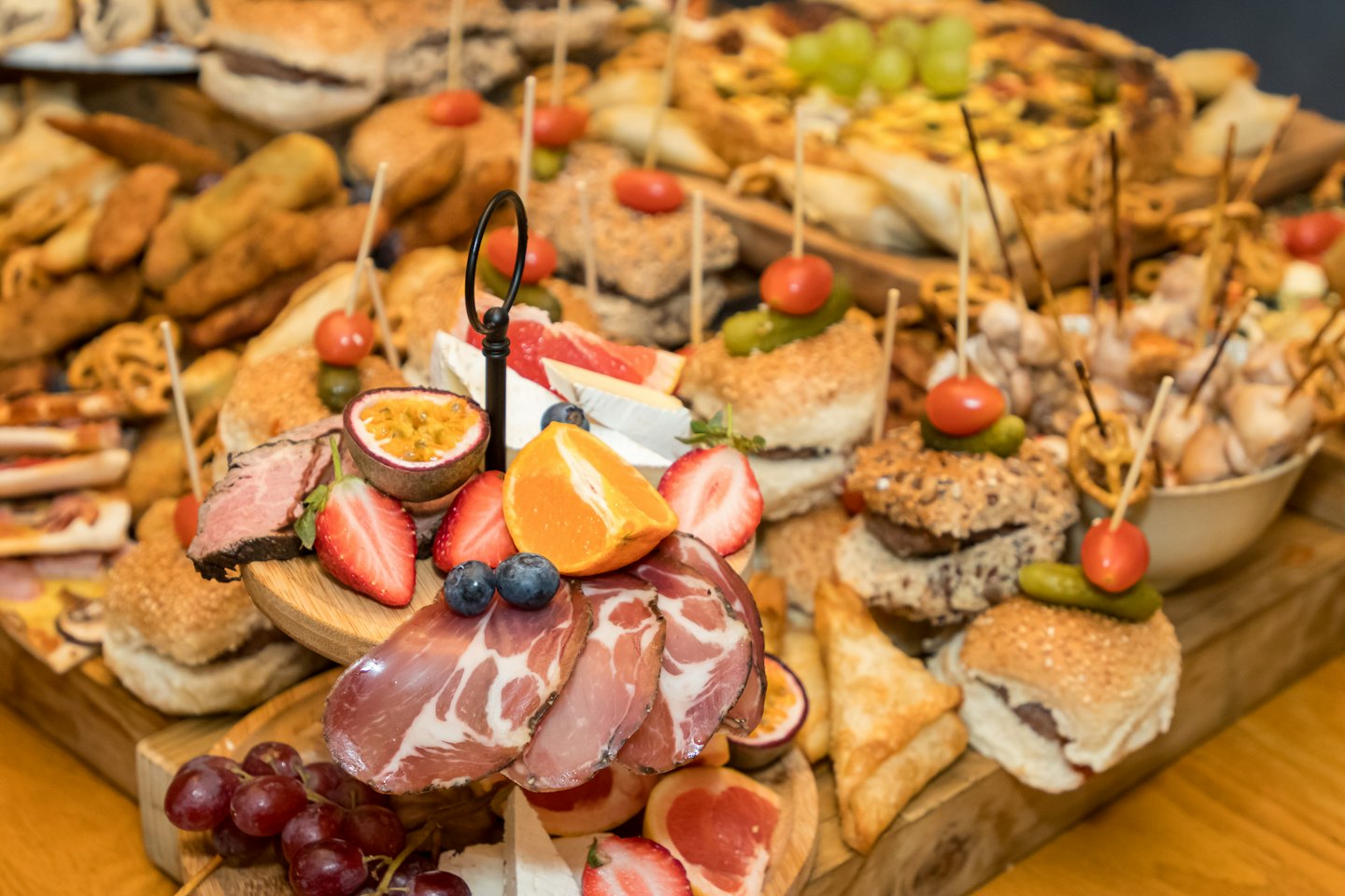 Assortiment de petits fours et fruits frais disposés sur des planches en bois.